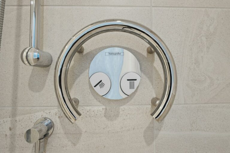 Caregiver assists an older adult using a walker beside bathroom grab bars and an emergency call button.